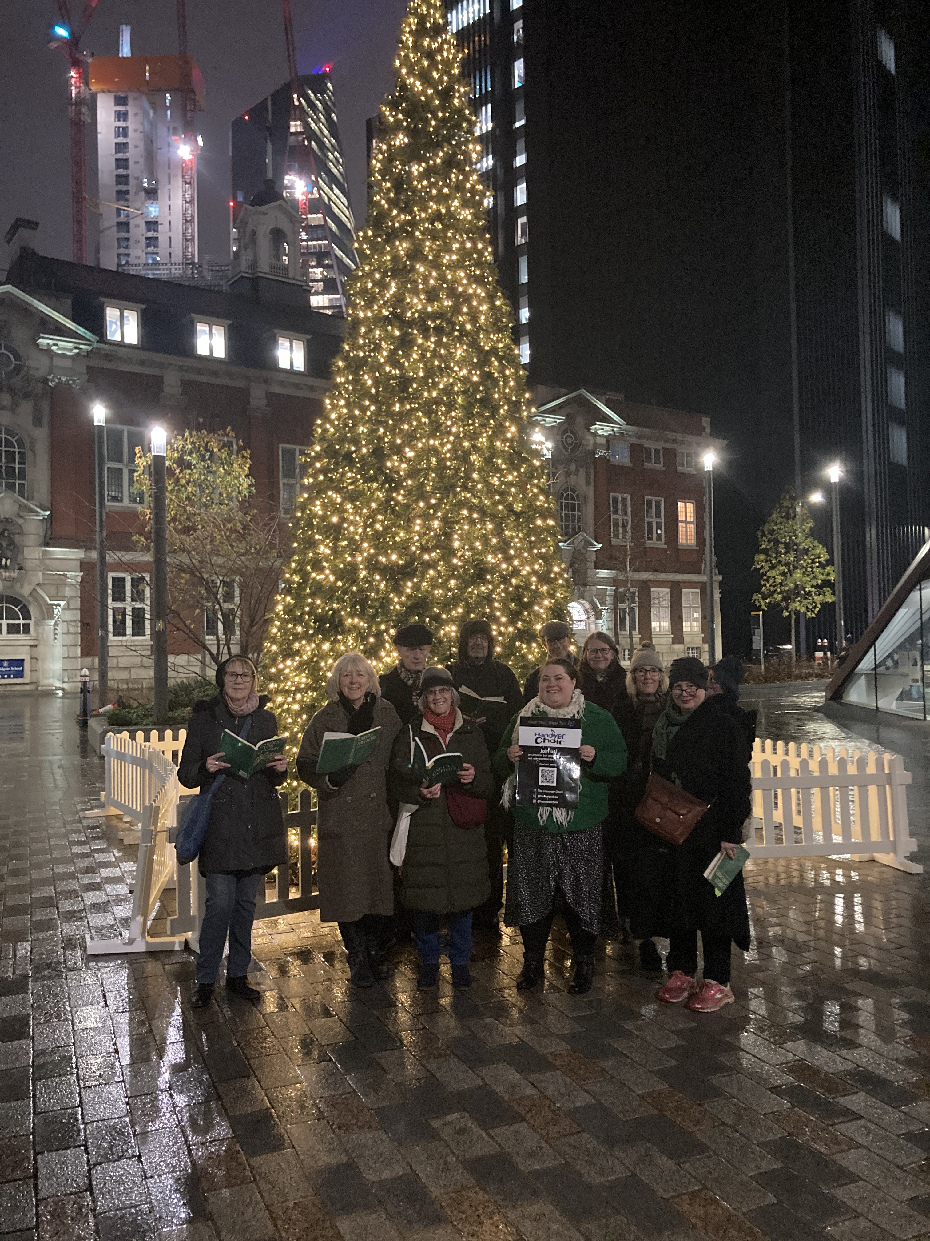 Choir carolling in front of a Christmas tree